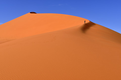 Algerien, Sahara, Tassili N'Ajjer National Park, Tadrart, Frau wandert auf den Sanddünen von Tin Merzouga, lizenzfreies Stockfoto