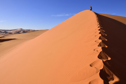Algerien, Sahara, Tassili N'Ajjer National Park, Tadrart, Frau wandert auf einer Düne von Tin Merzouga, lizenzfreies Stockfoto