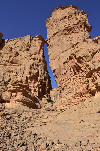 Algerien, Sahara, Tassili N'Ajjer Nationalpark, Tassili Tadrart, Frau beim Wandern in der felsigen Landschaft des Kars, lizenzfreies Stockfoto