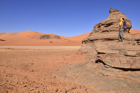 Algerien, Sahara, Tassili N'Ajjer National Park, Frau steht auf Felsen in Tin Merzouga, lizenzfreies Stockfoto