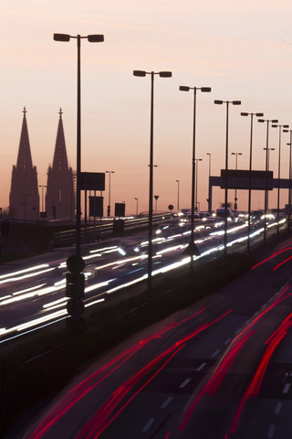 Germany, North Rhine-Westphalia, Cologne Cathedral and road traffic on lighted Zoobruecke at dusk stock photo