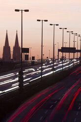 Deutschland, Nordrhein-Westfalen, Kölner Dom und Straßenverkehr auf der beleuchteten Zoobrücke in der Abenddämmerung - JATF000522