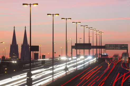 Deutschland, Nordrhein-Westfalen, Kölner Dom und Straßenverkehr auf der beleuchteten Zoobrücke in der Abenddämmerung - JATF000523