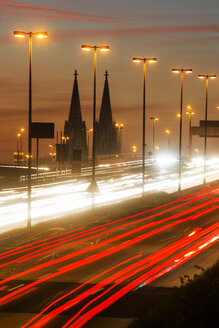 Deutschland, Nordrhein-Westfalen, Kölner Dom und Straßenverkehr auf der beleuchteten Zoobrücke in der Abenddämmerung - JAT000525