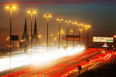 Deutschland, Nordrhein-Westfalen, Kölner Dom und Straßenverkehr auf der beleuchteten Zoobrücke in der Abenddämmerung - JAT000524