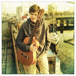junge hält seine Gitarre an einer Kaimauer, Deutschland, Hamburg - SEF000309