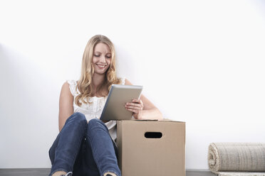 Smiling young woman with cardboard box and tablet computer - PDF000604