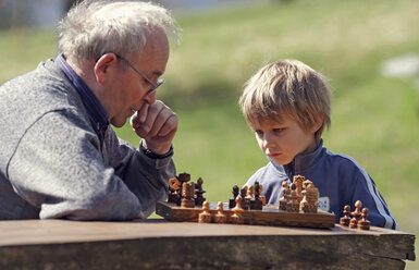 Germany, Rhineland-Palatinate, Leutesdorf, grandfather and grandson playing chess - PAF000258