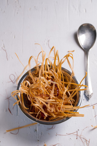 Schüssel mit ungekochten Chili-Nudeln mit Chili-Schoten und Chili-Fäden auf weißem Holztisch, lizenzfreies Stockfoto