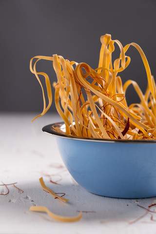 Schüssel mit ungekochten Chili-Nudeln mit Chili-Schoten und Chili-Fäden auf weißem Holztisch, lizenzfreies Stockfoto