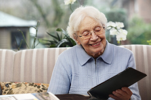 Lächelnde Seniorinnen beim Betrachten alter Fotos zu Hause - BIF000267