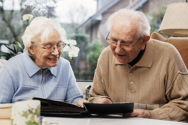 Senior couple watching old photographs at home - BIF000268