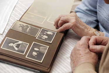 Senior couple watching old photograph album at home - BIF000273