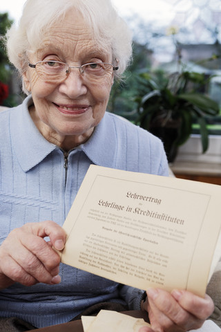 Ältere Frauen zeigen ihren alten Ausbildungsvertrag, lizenzfreies Stockfoto