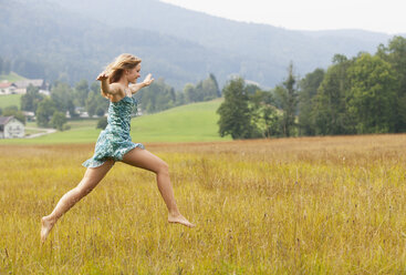 Austria, Salzkammergut, Mondsee, young woman jumping in a meadow - WWF003168