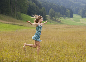 Austria, Salzkammergut, Mondsee, young woman running in a meadow - WWF003211