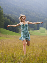 Austria, Salzkammergut, Mondsee, young woman with outstretched arms running in a meadow - WWF003169