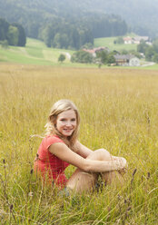 Österreich, Salzkammergut, Mondsee, junge Frau sitzt auf einer Wiese - WWF003176