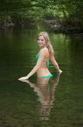 Austria, Salzkammergut, Mondsee, young woman bathing in a brook - WWF003184