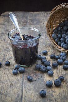Wickerbasket with blueberries (Vaccinium myrtillus) and glass of blueberry jam on wooden table - LVF000431