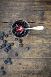 Heidelbeeren (Vaccinium myrtillus) und Glas Heidelbeermarmelade mit Löffel auf Holztisch - LVF000429