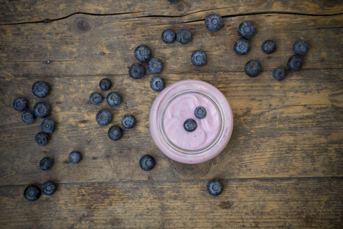 Heidelbeeren (Vaccinium myrtillus) und ein Glas Heidelbeerjoghurt auf einem Holztisch - LVF000428