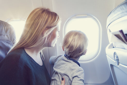 Mutter mit Sohn im Flugzeug schaut aus dem Fenster - MF000720