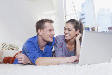 Couple at home lying on carpet and using laptop - RBF001532