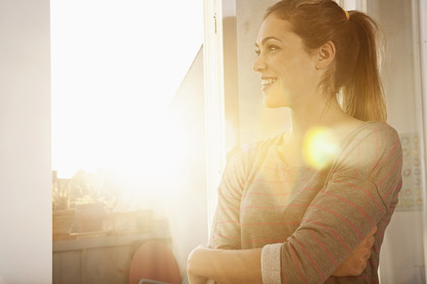 Portrait of happy woman standing at open window stock photo