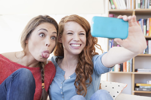 Zwei junge Freundinnen fotografieren sich selbst mit dem Smartphone, lizenzfreies Stockfoto