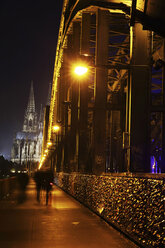 Deutschland, Nordrhein-Westfalen, Köln, beleuchteter Kölner Dom und Hohenzollernbrücke mit Fußgängern bei Nacht - JATF000551