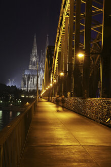Deutschland, Nordrhein-Westfalen, Köln, beleuchteter Kölner Dom und Hohenzollernbrücke mit Fußgängern bei Nacht - JATF000555