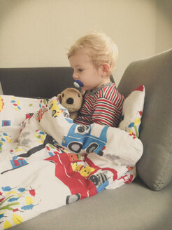 Kleiner Junge krank, sitzt mit Schlafsack auf der Couch - MEAF000056