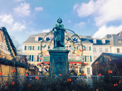 Beethoven-Statue vor Riesenrad und Altem Postamt auf dem Münsterplatz während des Weihnachtsmarktes, Bonn, Nordrhein-Westfalen, Deutschland, lizenzfreies Stockfoto