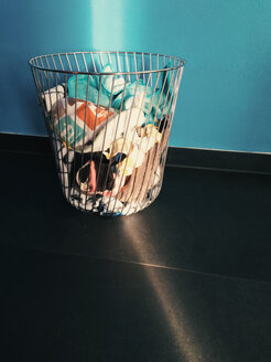 Laundry basket being hit by ray of sunlight in front of a blue wall - MEAF000062