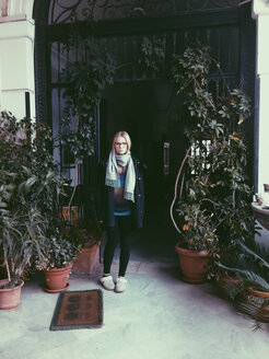 Young woman standing on balcony with plants, Palermo, Sicily, Italy - MEAF000106