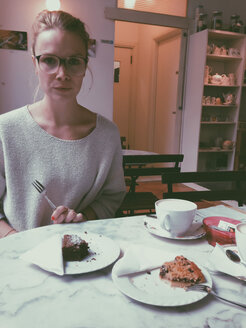 Young woman at coffee and cake table, looking at camera, Palermo, Sicily, Italy - MEAF000088