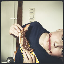child eats chocolate hazelnut bread, chocolate-smeared mouth - SBDF000412