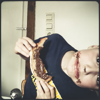 kind isst Schokoladen-Haselnuss-Brot, Mund mit Schokolade beschmiert - SBDF000412