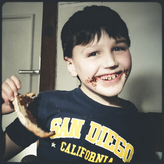 Kind isst Schokoladen-Haselnuss-Brot, Mund mit Schokolade verschmiert, Deutschland - SBDF000410