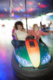 Germany, Herne, Two young women riding bumper cars at the fairground - BGF000067