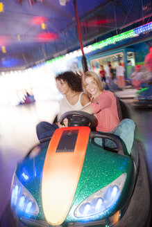 Germany, Herne, Two young women riding bumper cars at the fairground - BGF000066