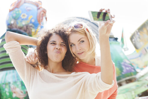 Germany, Herne, Two young women at the fairground photographing self - BGF000057