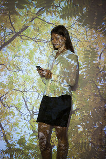 Junge Frau in Naturprojektion mit Smartphone - BGF000083