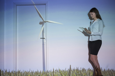 Young woman with projection of wind turbine using digital tablet stock photo