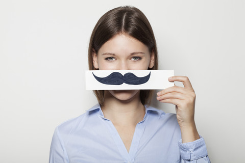 Young woman covering part of face with painted moustache stock photo