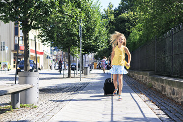 Mädchen mit Ziehkoffer läuft auf Gehweg - VTF000057