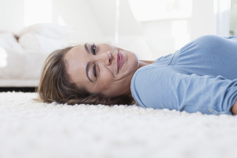 Frau auf Teppich liegend blinzelnd, lizenzfreies Stockfoto
