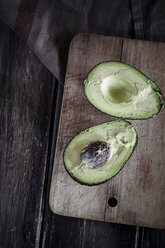 Sliced avocado on chopping board and wooden table - SBDF000462