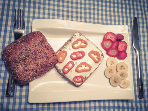 Gesundes Frühstück mit Ciabatta-Vollkornbrötchen, Frischkäse mit geschnittener Paprika und Obst, lizenzfreies Stockfoto